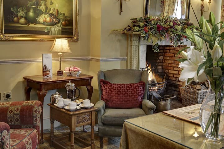 Cozy York Pavilion Hotel lounge with fireplace, floral decor, armchairs, and tea set on a wooden table.