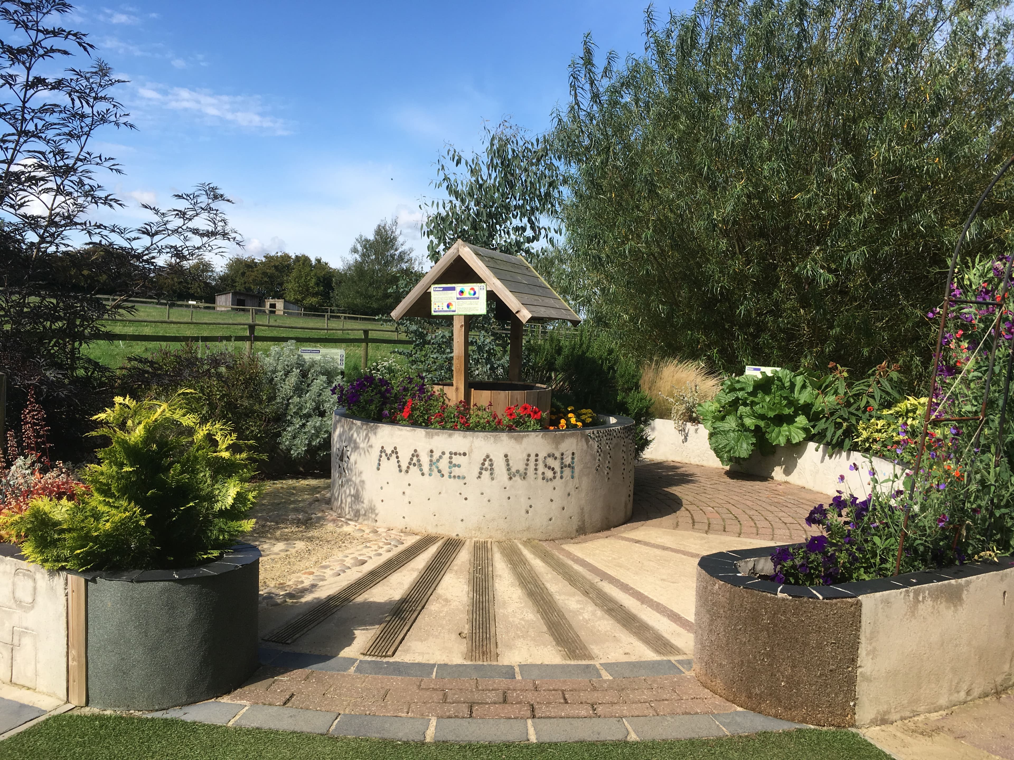 Lush Sensory Garden with a wishing well surrounded by many textured surfaces, flowers and greenery