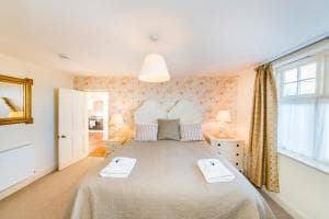 Bright, cozy bedroom in Sands Apartment, Whitby, with a double bed, patterned wallpaper, and soft lighting.