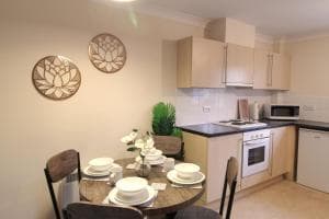 Modern kitchen in Sunnydale Apartments, Wakefield, with wooden table, white dishes, and decorative wall art.