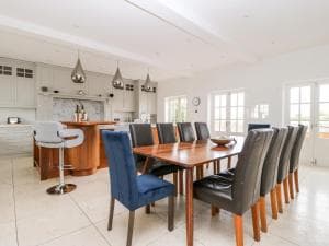 Spacious kitchen in Green End House, Ripon, featuring a wooden dining table, modern chairs, and sleek gray cabinetry.