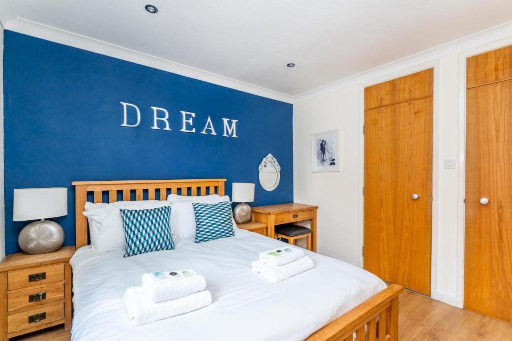 Bedroom in St George's House, York, with wooden furniture, blue accent wall, and "DREAM" decor.