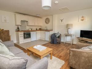 Cozy interior of The Byre cottage, Hood Grange, with modern kitchen, wooden floors, and comfortable seating.
