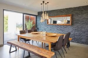 Modern dining room in Otterhill, Great Ayton, featuring a rustic wooden table, sleek chairs, and stone accent wall.