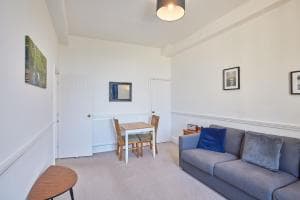 Bright living room in The Observatory Apartment, Marske, featuring a gray sofa, dining table, and framed wall art.