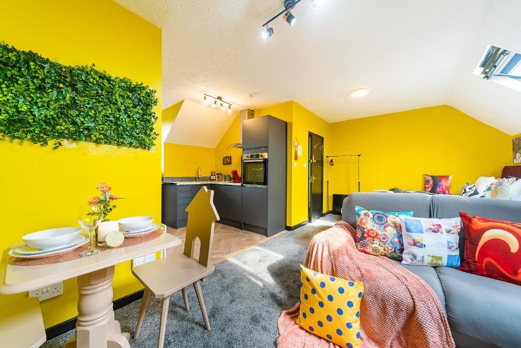 Bright, cozy apartment in Hull with yellow walls, modern kitchen, and colorful cushions creating a cheerful atmosphere.