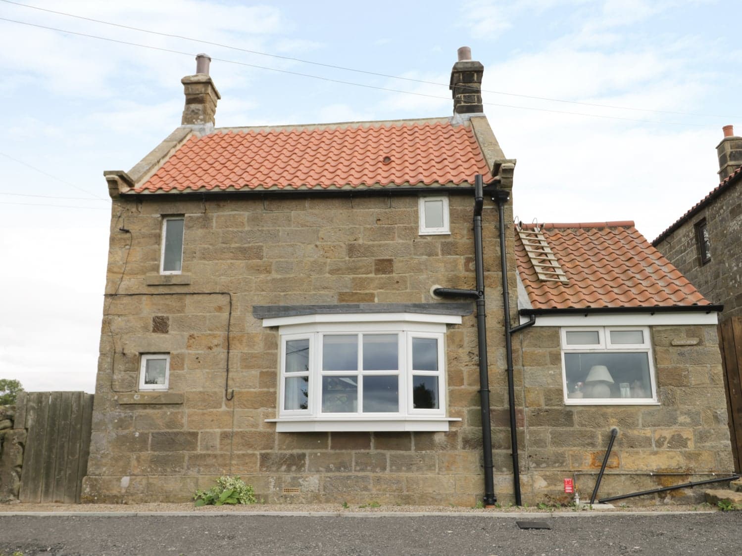 Swang Cottage in Glaisdale, Yorkshire, with stone walls, red-tiled roof, and a bay window under a cloudy sky.