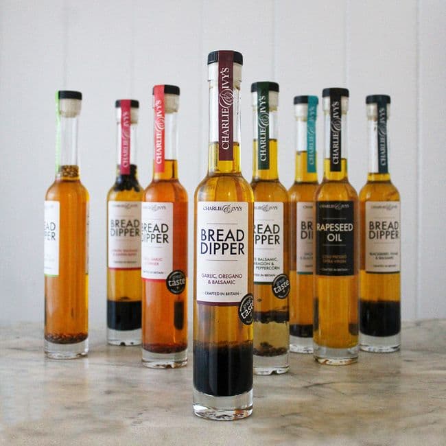 A selection of Charlie & Ivy's colorful bread dipper bottles arranged on a marble surface, showcasing various flavors.