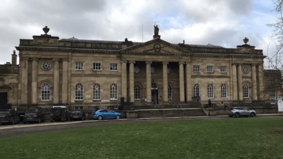 Historic stone courthouse in York, featuring grand columns and large windows, set against a cloudy sky.