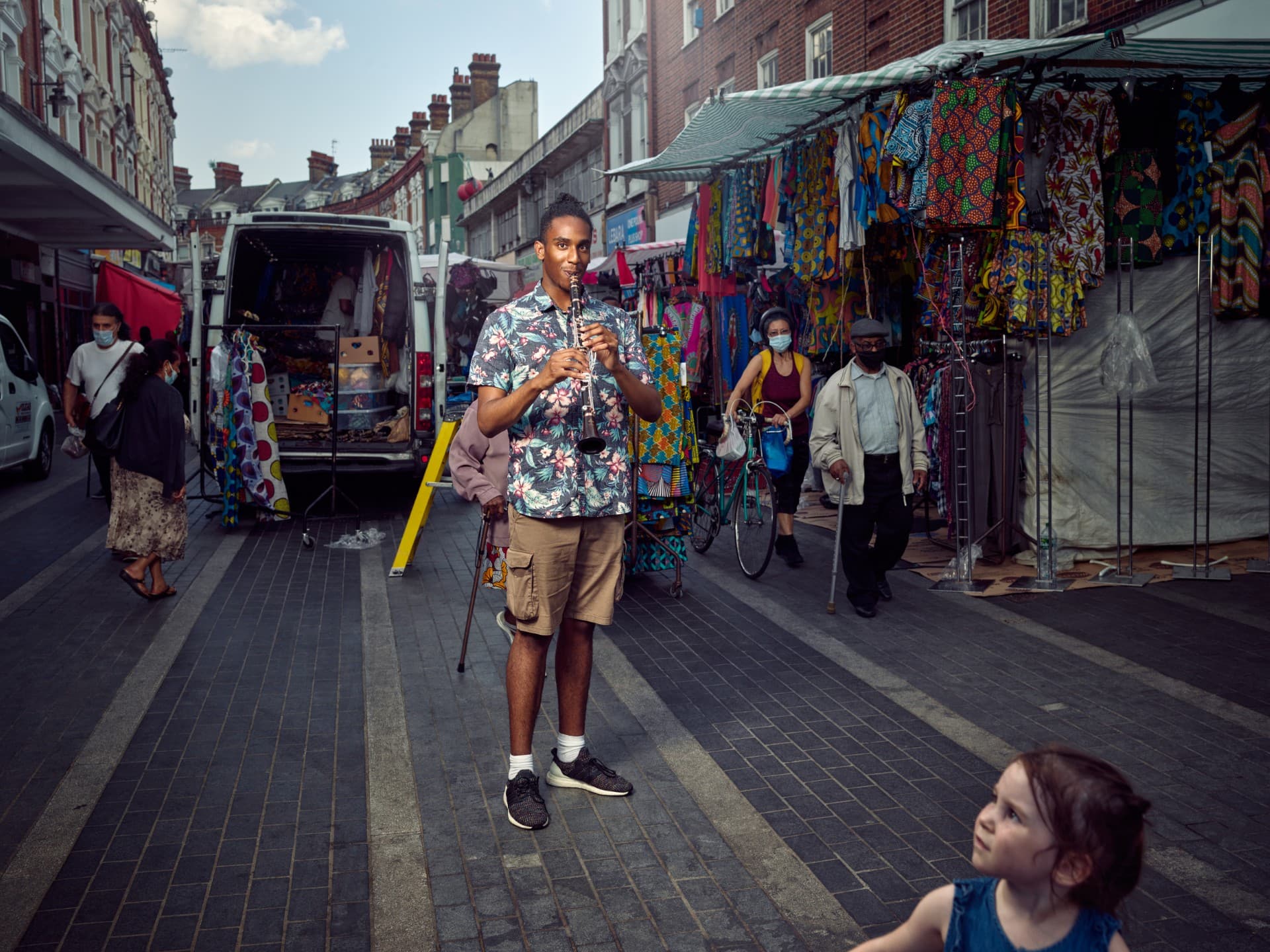 A bustling market scene in Harrogate, with vibrant stalls, a musician playing, and people enjoying the lively atmosphere.
