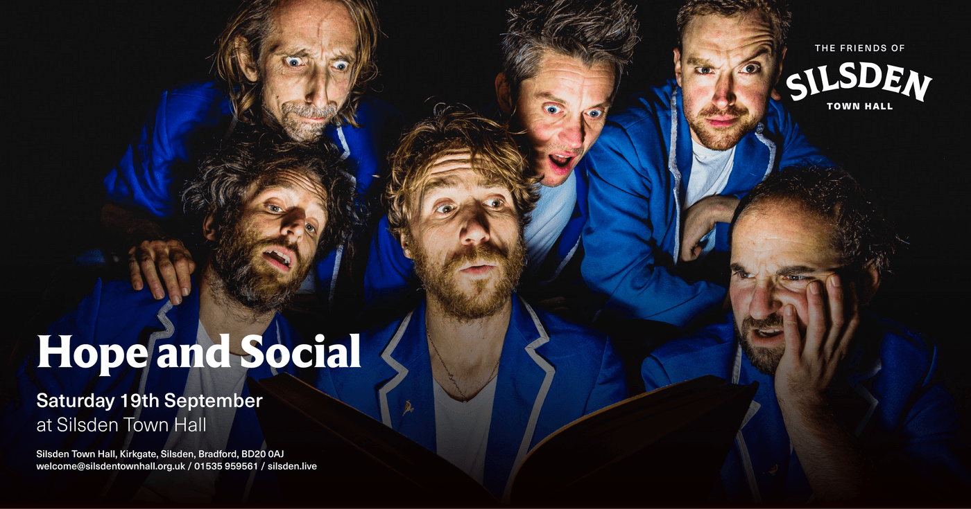 A lively group of musicians in blue blazers performing at Silsden Town Hall, creating an energetic and engaging atmosphere.