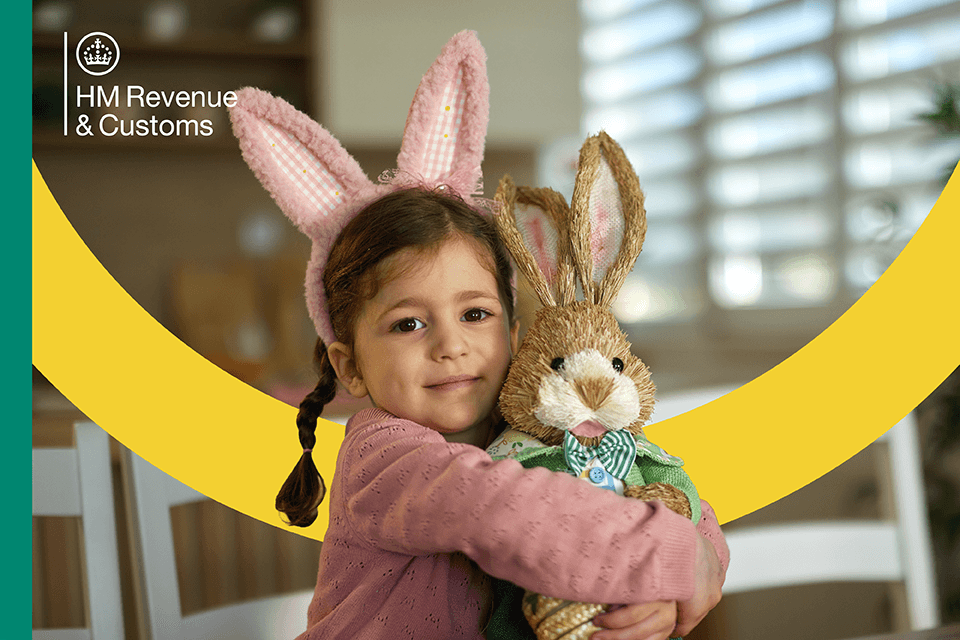 A young girl in bunny ears hugs a plush rabbit toy, sitting in a bright, cheerful room.