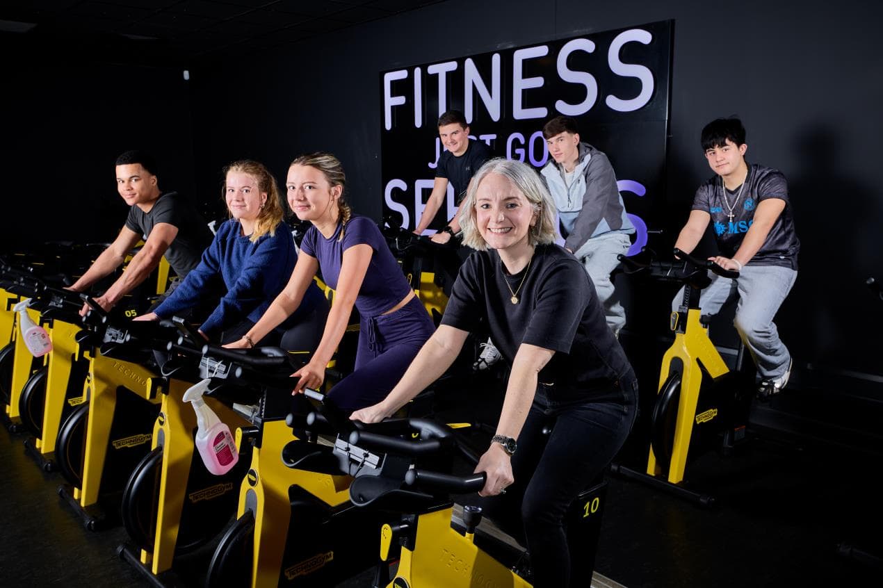 Young people on stationary bikes in a modern fitness studio, promoting active lifestyles in Wakefield.