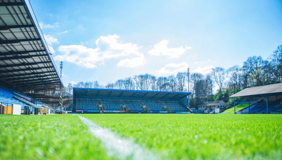 Sunny football stadium with green field and empty stands