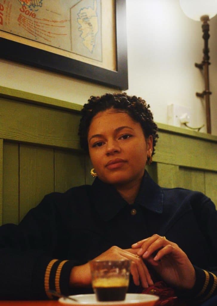 Nectar Woode sitting in cozy cafe with espresso on table