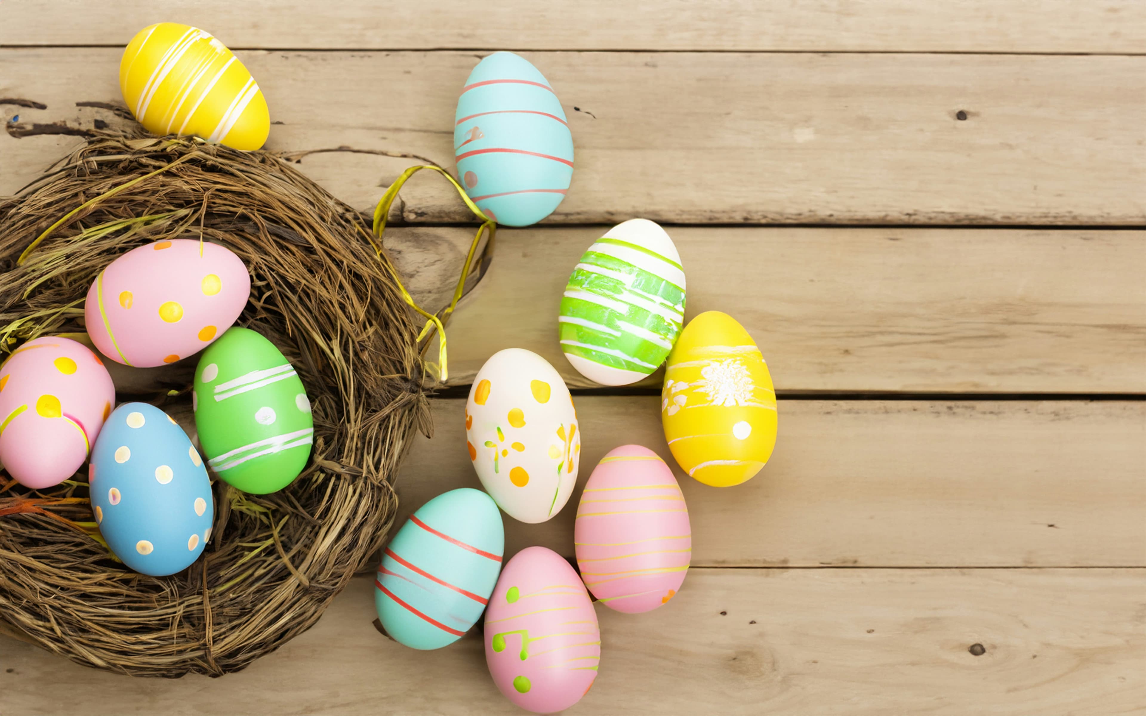 Colorful decorated Easter eggs in nest on wooden table