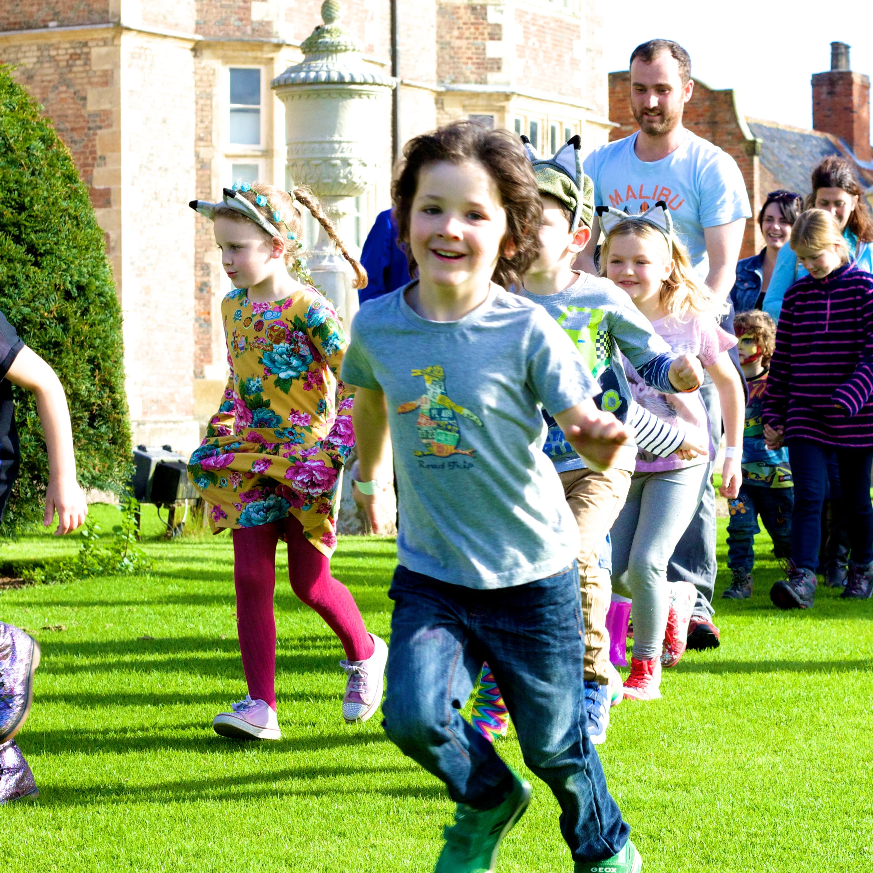 Children playing on lush green lawn in front of historic manor