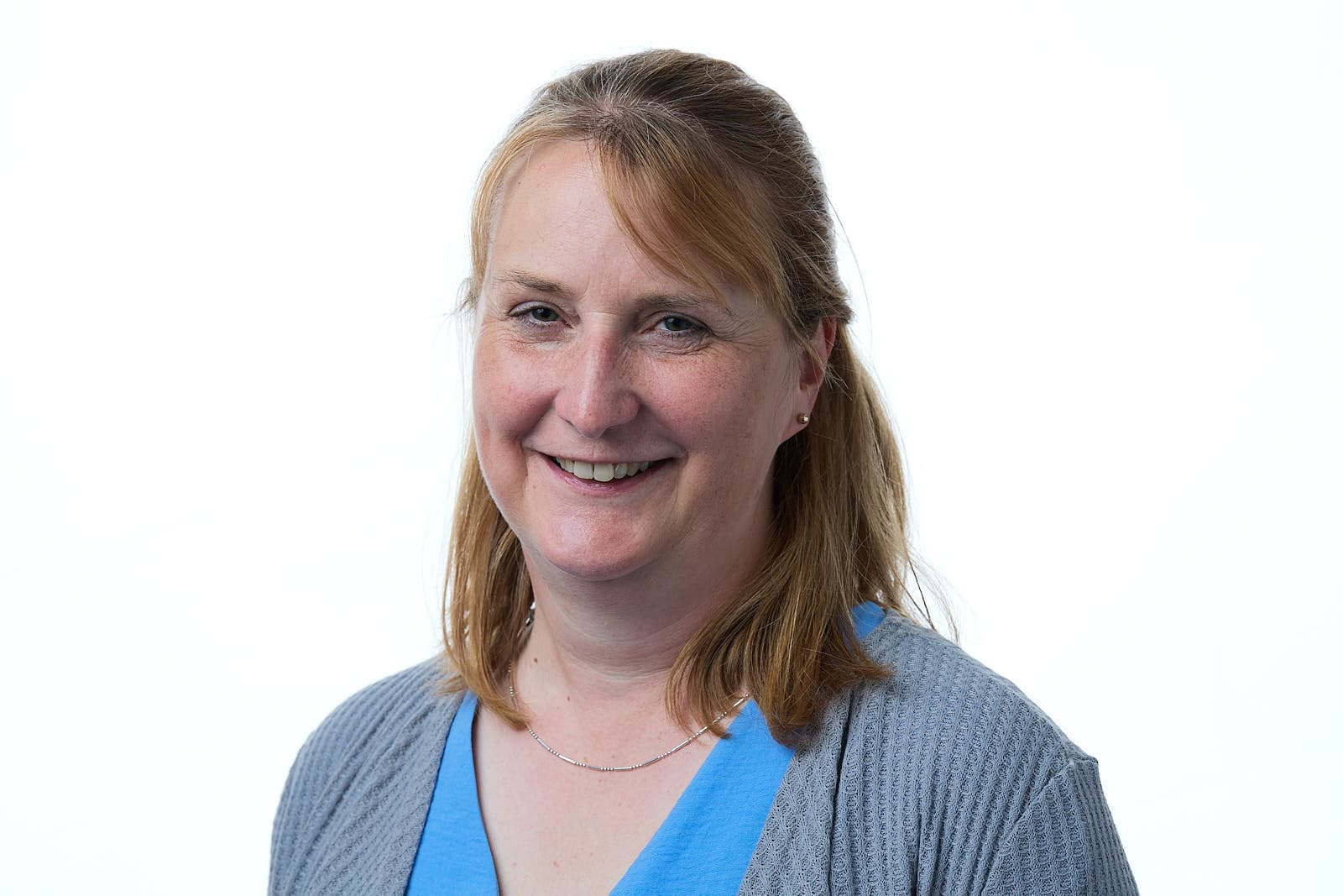 Smiling person with light brown hair in a blue shirt