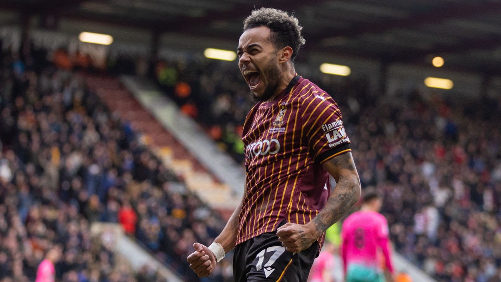 Football player celebrating in striped jersey at crowded stadium