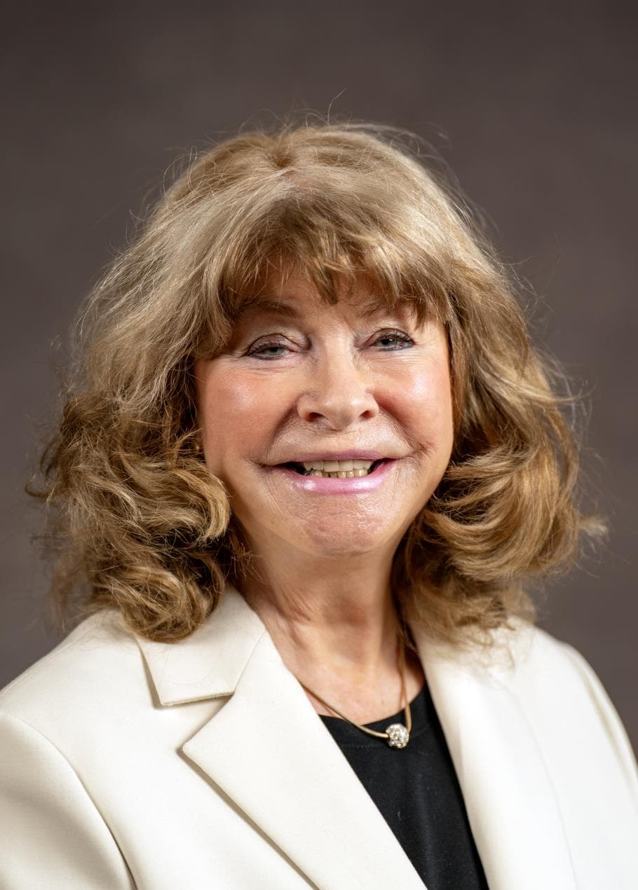 Smiling person with curly hair in beige blazer