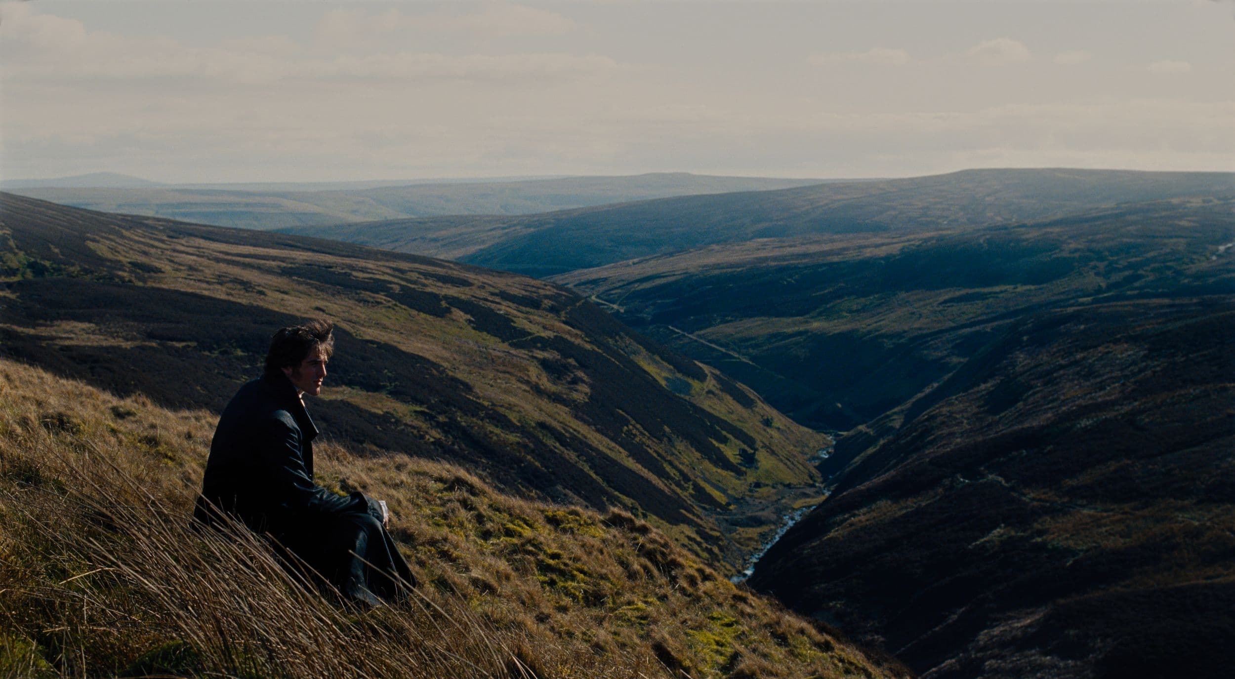 Person sitting on grassy hill overlooking Yorkshire moors