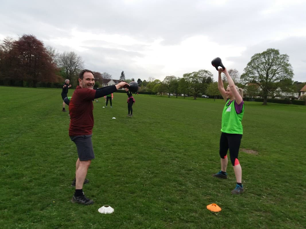 Participants engaged in outdoor fitness training at Army Fit Addingham Bootcamp, with kettlebells and cones on the grass.