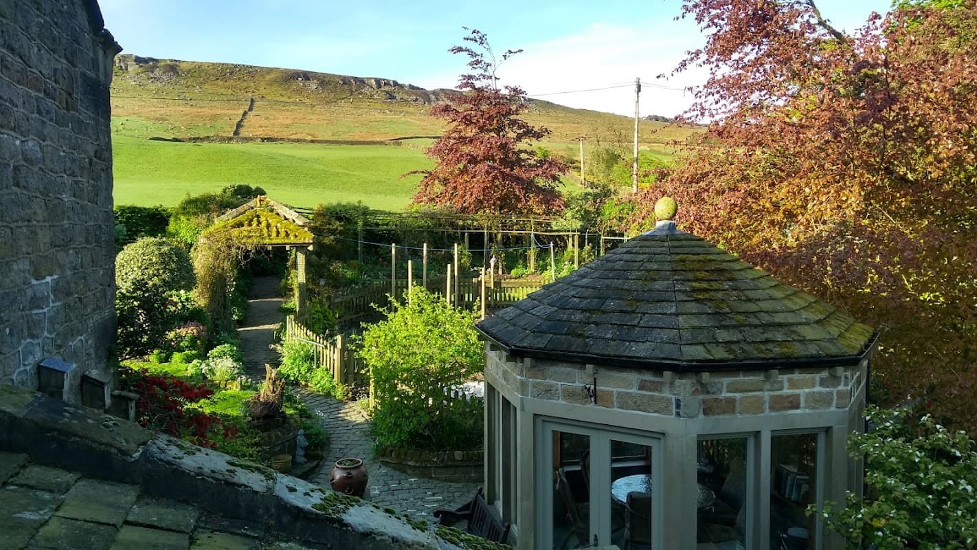 Charming farmhouse with a garden, gazebo, and scenic hills in the background, set in Addingham, Yorkshire.