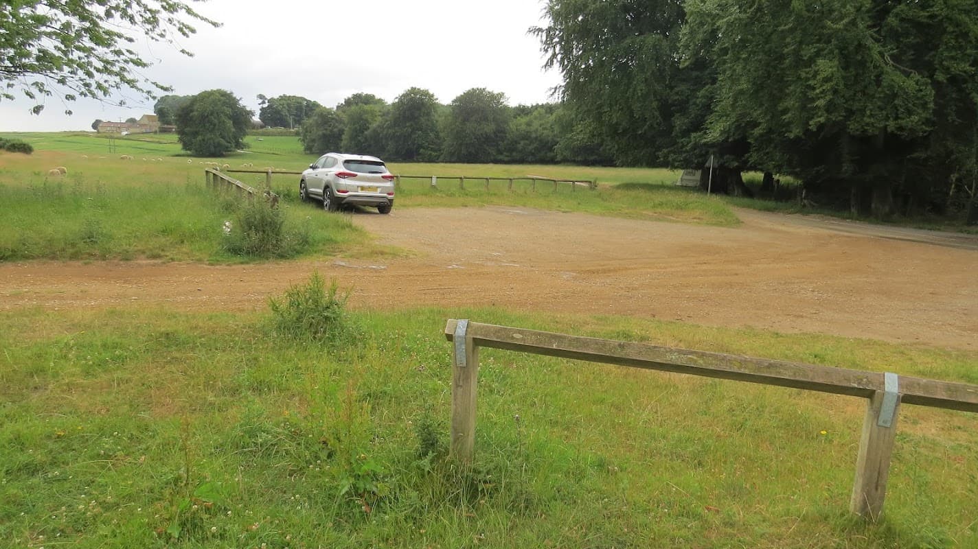 Gravel car park with a white SUV, surrounded by lush greenery and trees, near a rural road in Allerston, Yorkshire.