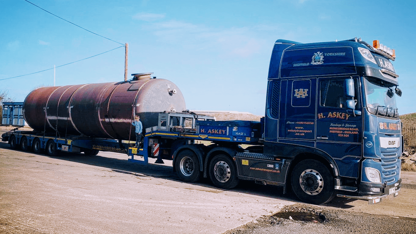 A blue H. Askey truck parked next to a large cylindrical tank on a trailer in Anston, Yorkshire.