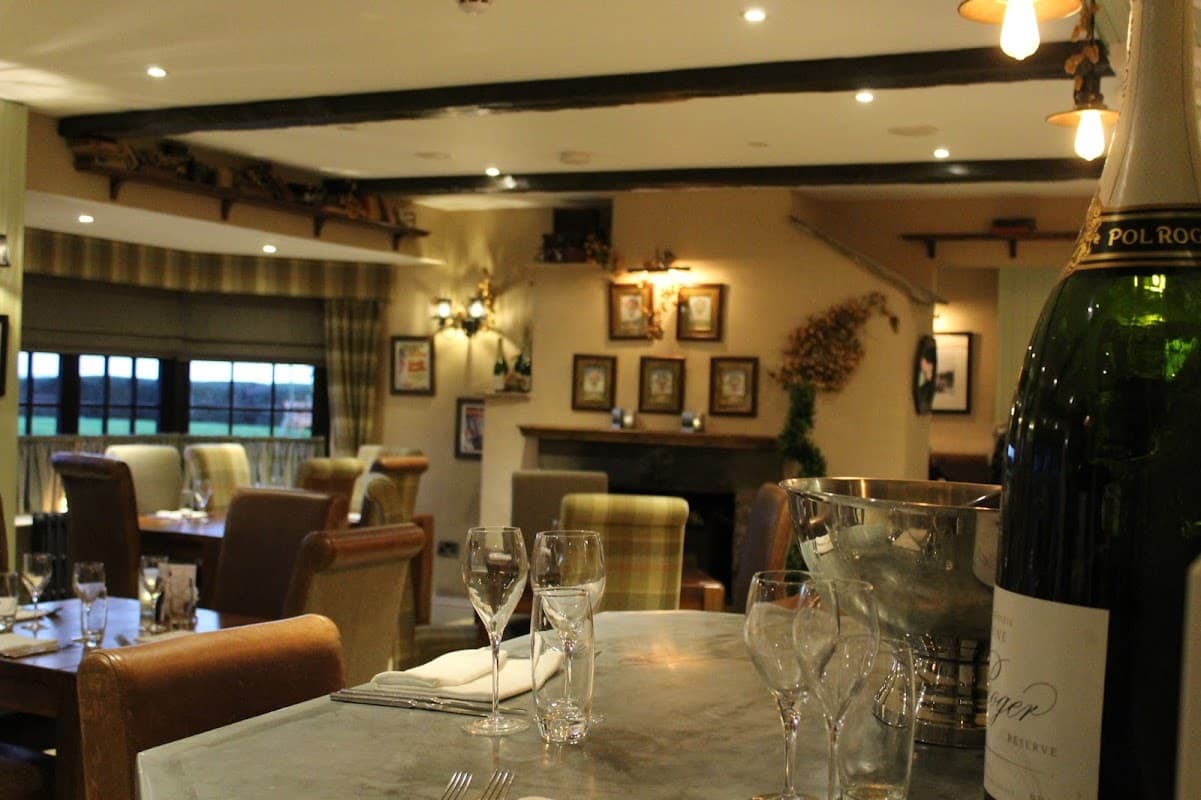 Cozy dining area with wooden beams, elegant table settings, and a champagne bucket in the foreground.
