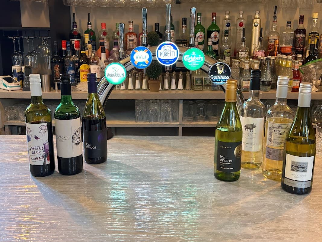 Bistro bar with various bottles of wine and spirits on display, illuminated by colorful signage in a cozy setting.