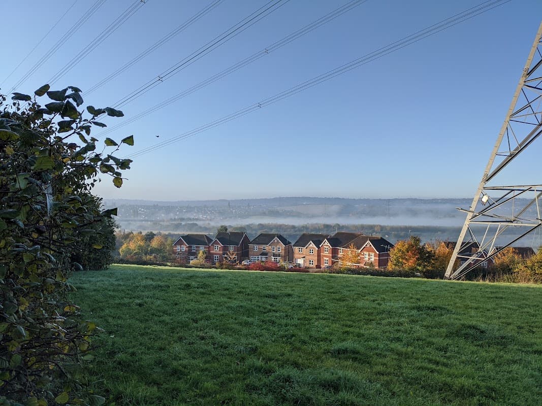 View of residential buildings in Aston, Yorkshire, with misty hills and power lines in the background.