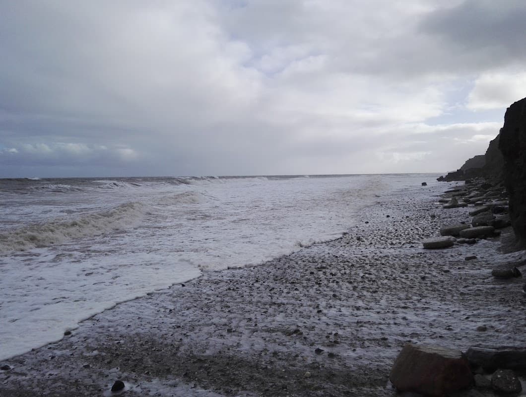 Stormy sea waves crashing on a pebbled shore under a cloudy sky at Skirlington Hornsea Road, Atwick, Yorkshire.