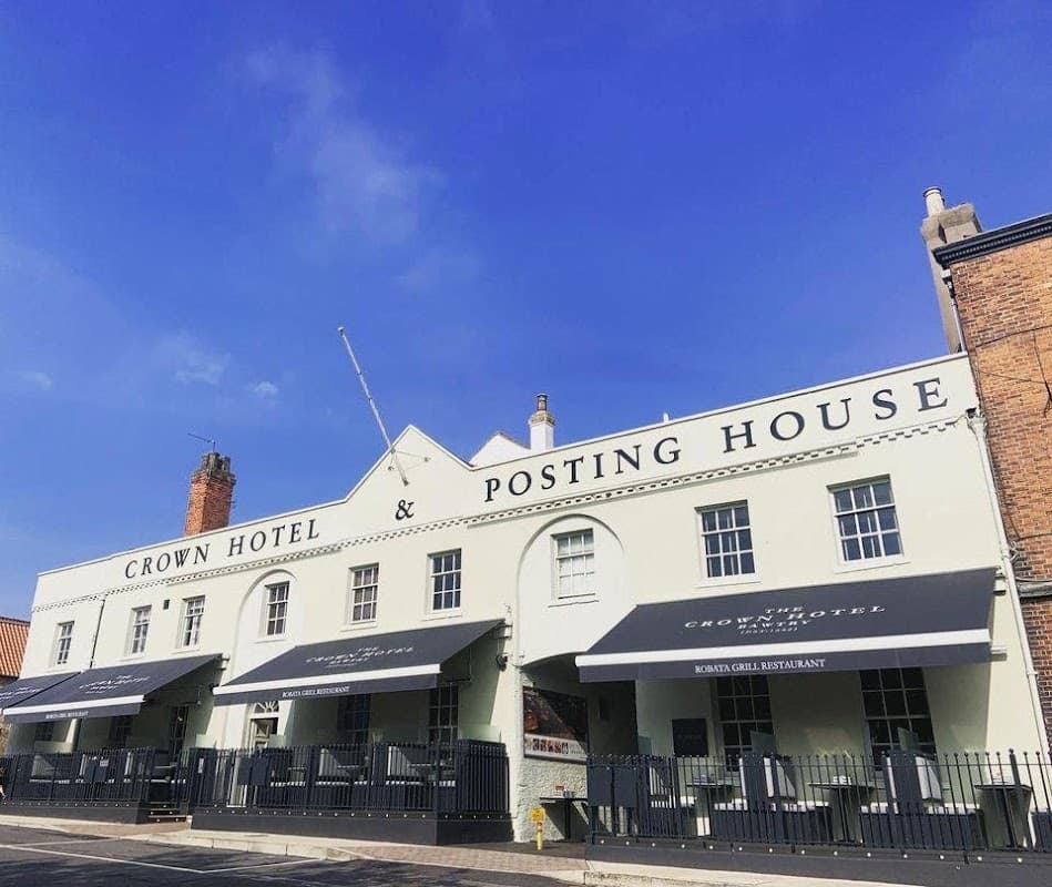 Crown Hotel & Posting House exterior with blue sky, awnings, and outdoor seating in Austerfield, Yorkshire.