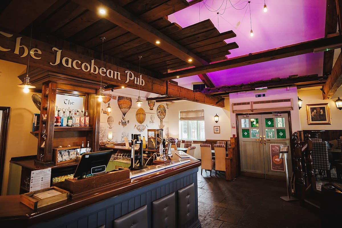Cozy interior of The Jacobean Pub, featuring a wooden bar, colorful decor, and soft lighting.