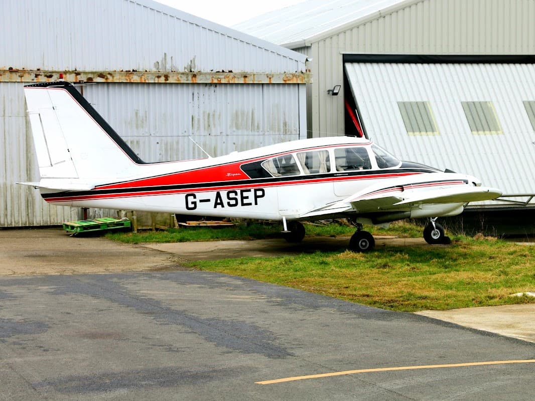 Light aircraft G-ASEP parked on tarmac near hangars at Bagby Airfield, surrounded by grass and buildings.