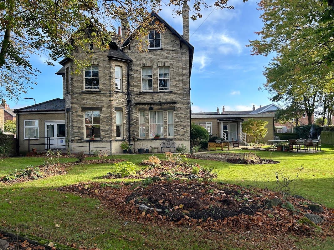 Victorian-style care home surrounded by gardens, trees, and outdoor seating in Barlby, Yorkshire.