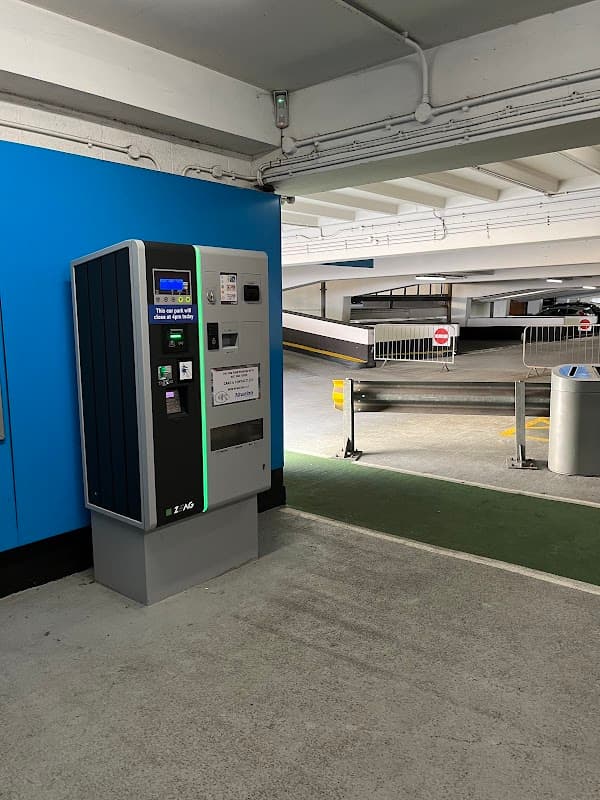 Pay & Display machine in a multi-storey car park, with barriers and an open parking area in the background.
