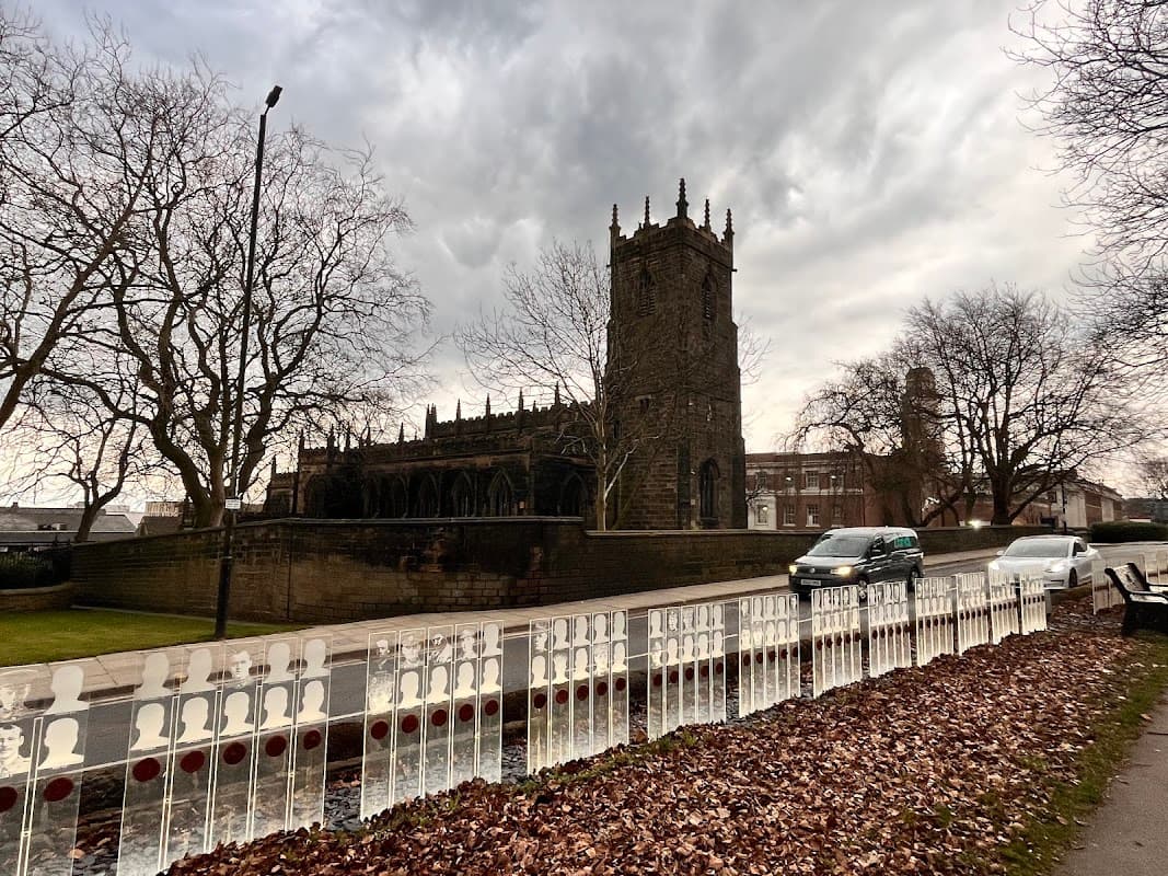 Churchfields Commuter Car Park with a church tower, bare trees, and a cloudy sky in Barnsley, Yorkshire.