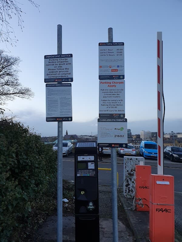 Signposts with parking charges and payment instructions beside a parking meter at Heelis Street Car Park in Barnsley.