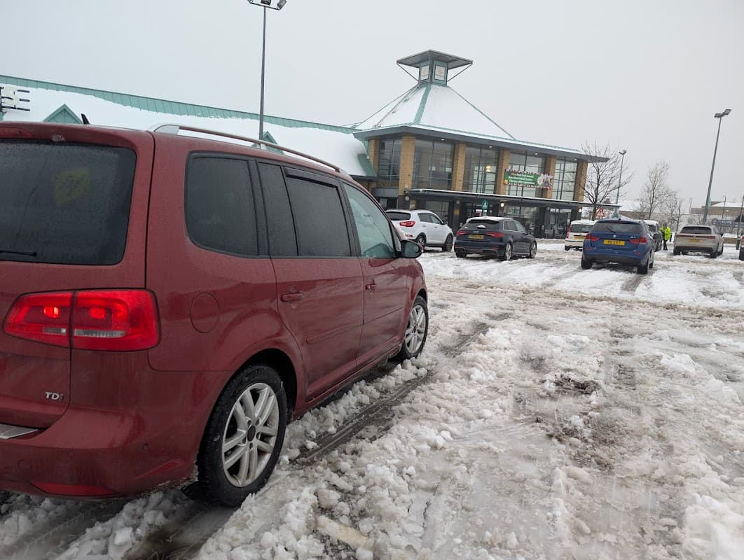 Red vehicle parked in a snowy Pay & Display lot outside a Morrison's store in Barnsley, Yorkshire.