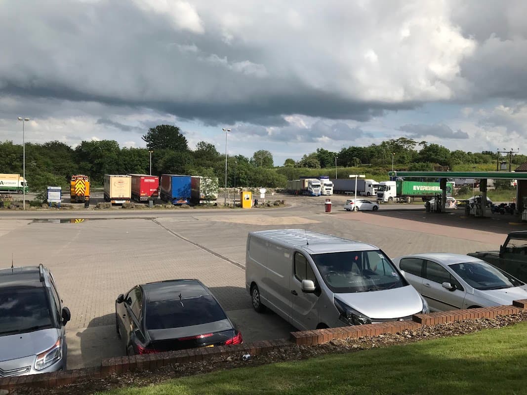 Trucks and vehicles parked at a service station in Barton, Yorkshire, under a cloudy sky.