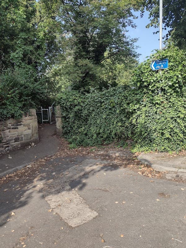 Entrance to the Wilton Park Greenway, surrounded by lush greenery and a directional sign indicating the path.