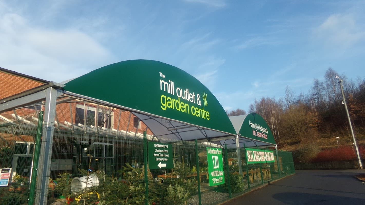 Green signage for "The Mill Outlet & Garden Centre" with a clear blue sky and trees in the background.