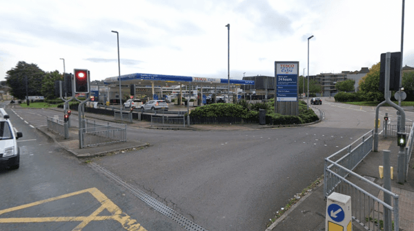 Tesco petrol station in Batley, Yorkshire, with cars and traffic lights visible on a cloudy day.