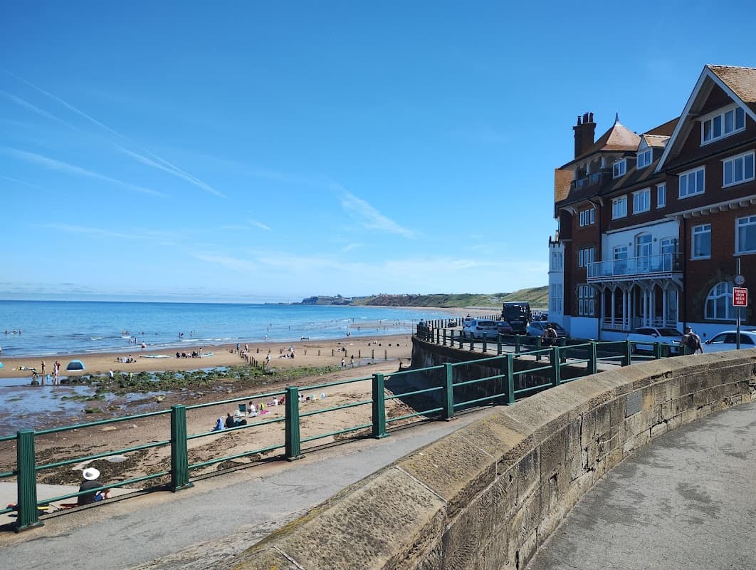 The Engine Shed at Battersby, a brick building with a sloped roof, near a sandy beach and clear blue sky.