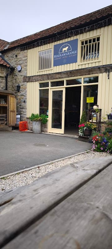 Beadlam Grange Farmshop and Tea Room with a welcoming entrance, stone walls, and vibrant flower pots.