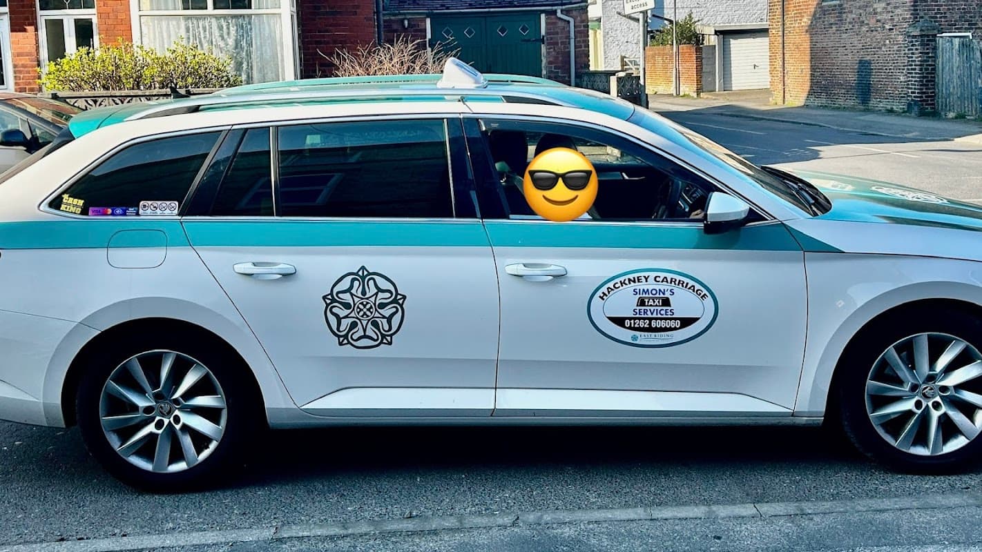 Green and white taxi with sunglasses emoji, parked in a street near a pub in Bessingby, Yorkshire.
