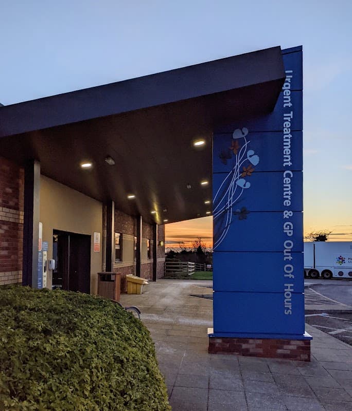 Beverley Urgent Treatment Centre entrance with a blue sign, modern architecture, and a sunset in the background.