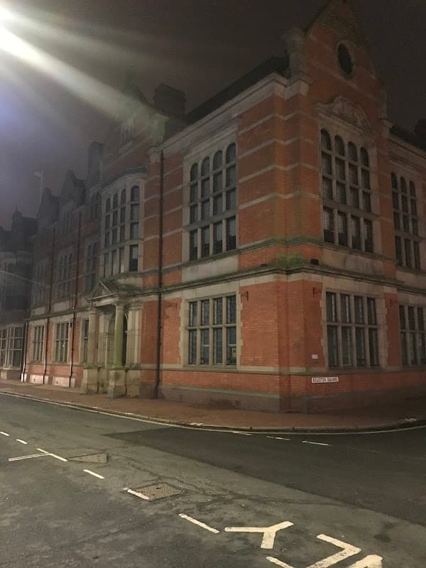 Historic brick building with large windows, corner tower, and street view in Beverley, Yorkshire at night.